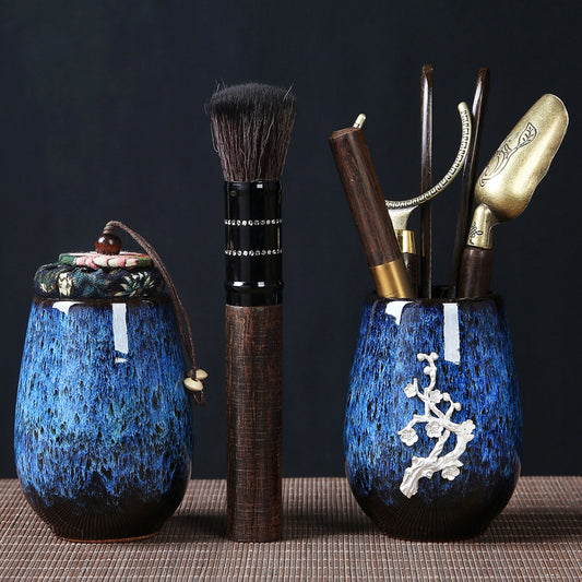 A black sandalwood tea ceremony set with a Buddha's hand design, including a tea pot, tea spoon, tea fork, tea knife, a pot care brush, and a tea clip, displayed on a dark background.
