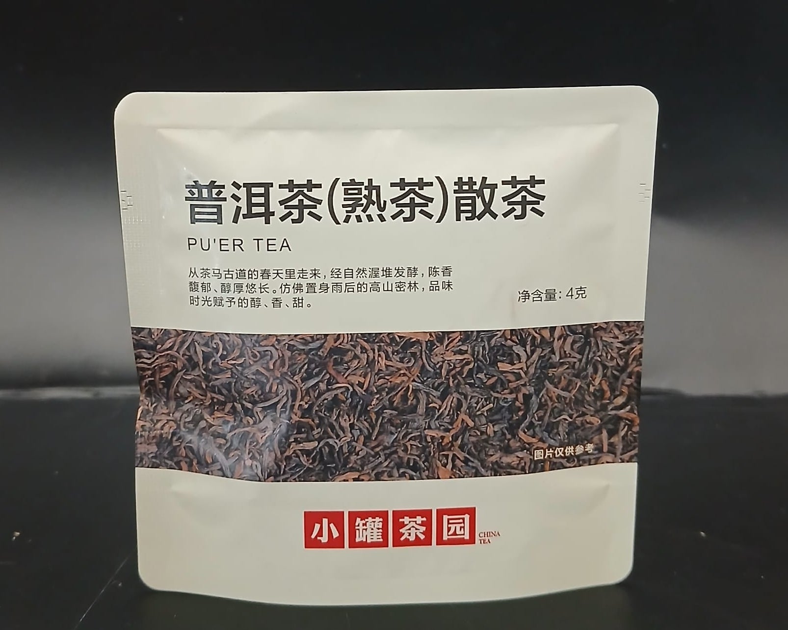 Tea package with text and a brand logo on a dark background